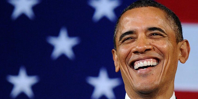 Barrack Obama smiling in front of American flag