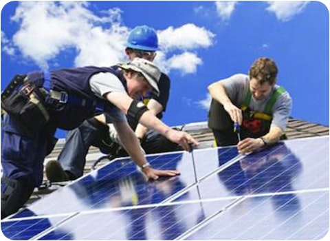 three solar installers installing solar panels on a tiled roof