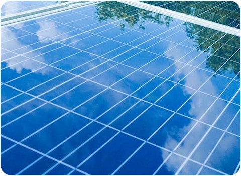 close up of 3 solar panels showing reflection of cloudy blue sky
