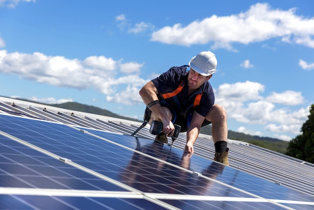 solar installer on roof checking solar panel tilt angle